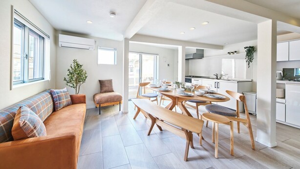 Una cocina moderna con armarios blancos, un comedor con mobiliario de madera y un amplio ventanal que proporciona luz natural.