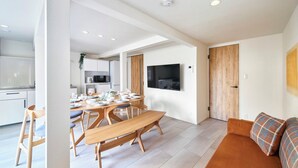 Un espacio habitable moderno con comedor, un sofá y un televisor montado en la pared.