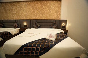 A hotel room with two beds, each with a headboard and bedside lamps.
