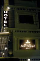 A hotel sign with the name "HOTEL SHRI VINAYAK" illuminated at night.