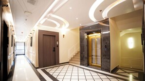 A modern hotel lobby with a marble floor, a central staircase, and a reception area. - Hotel Shri Vinayak (Varanasi)