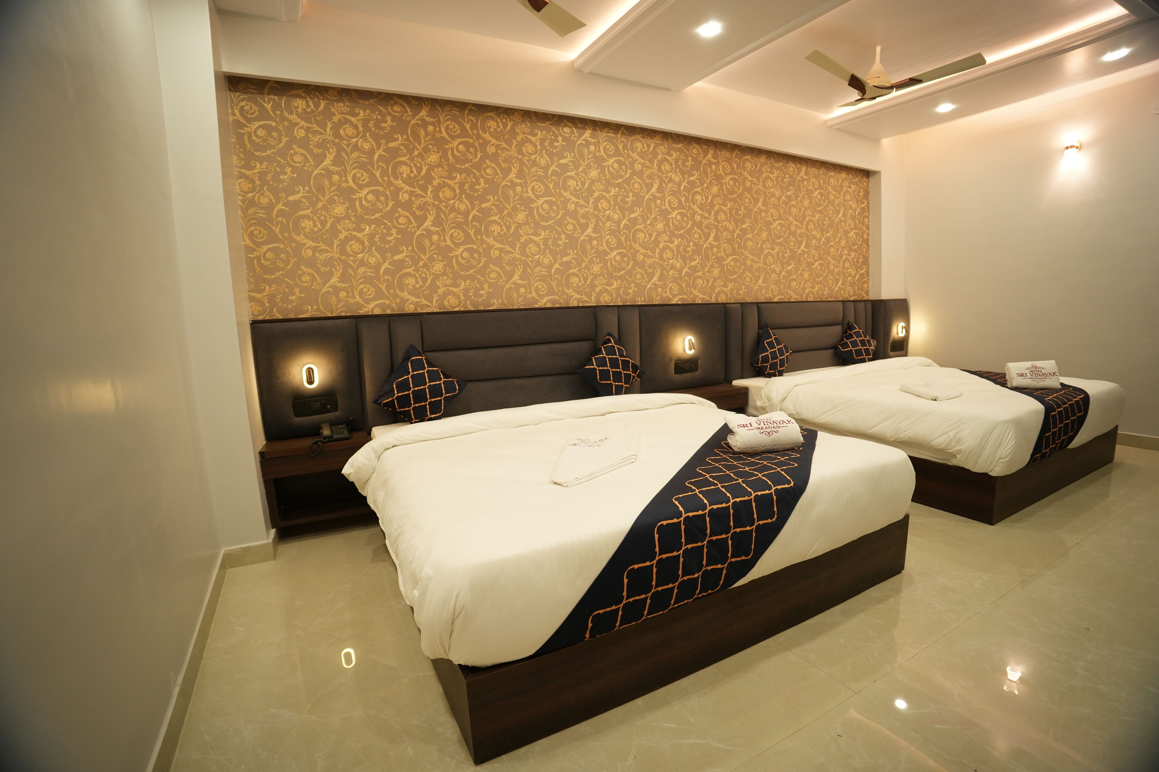 A hotel room with two beds, a decorative wall, and a ceiling fan.