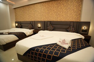 A hotel room with two beds, each with a headboard, bedside lamps, and decorative pillows.
