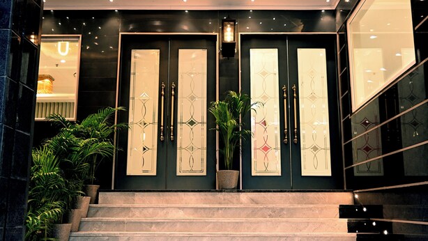 A grand entrance with a chandelier, double doors with intricate designs, and a staircase leading up to the entrance. - Hotel Shri Vinayak (Varanasi)