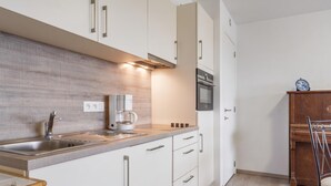 Une cuisine moderne avec des meubles blancs, un évier en acier inoxydable et une machine à café.
