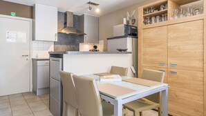 Eine kompakte Küche mit Essbereich, ausgestattet mit Kühlschrank, Herd und Schränken.