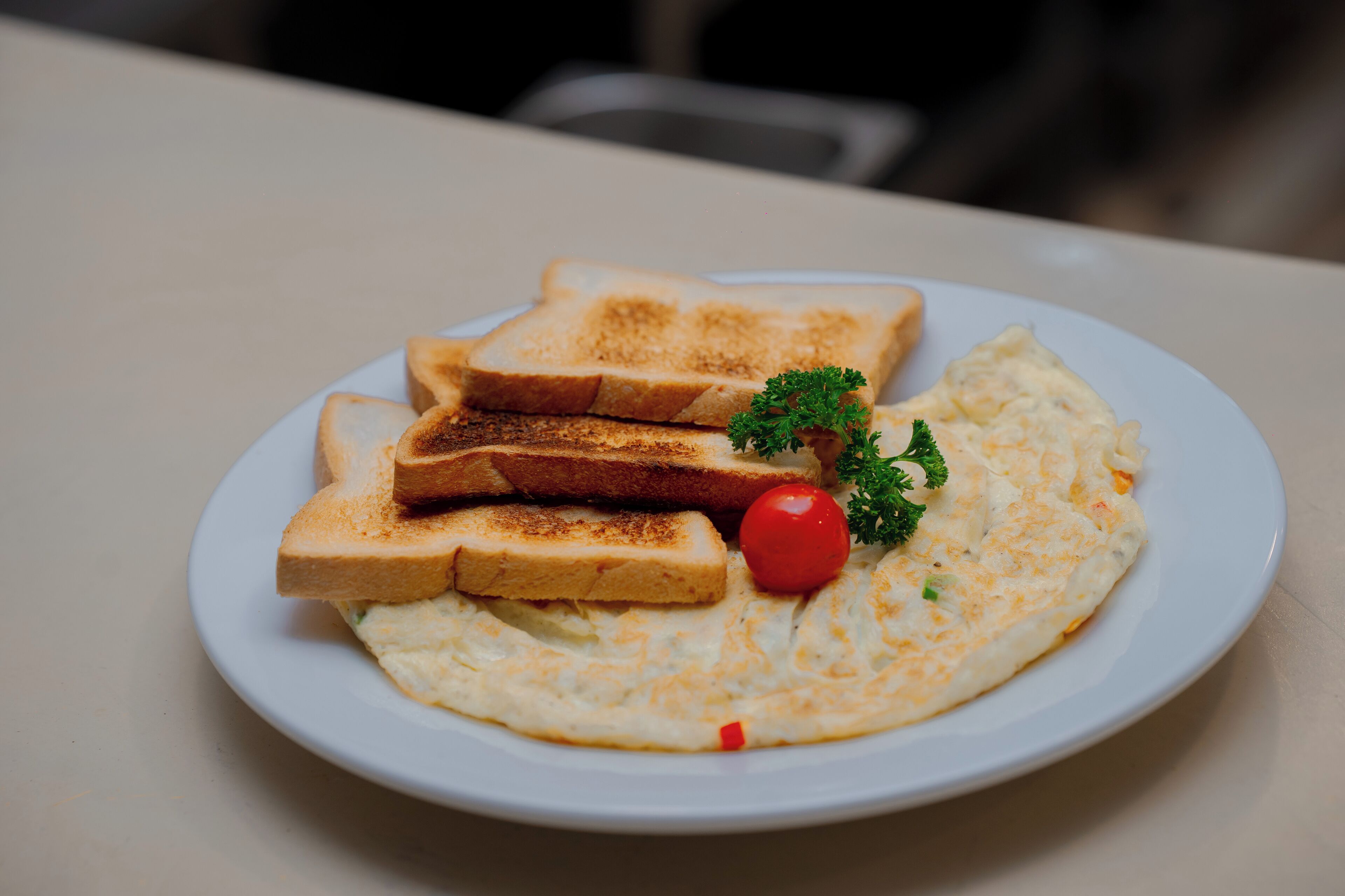 A plate with toast and an omelet, garnished with a cherry tomato and parsley.