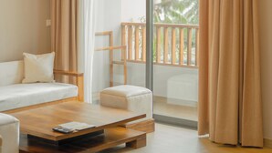 A modern living room with a sofa, a coffee table, and a view of a balcony with a railing. - Emerald Resort Hikkaduwa (Hikkaduwa)