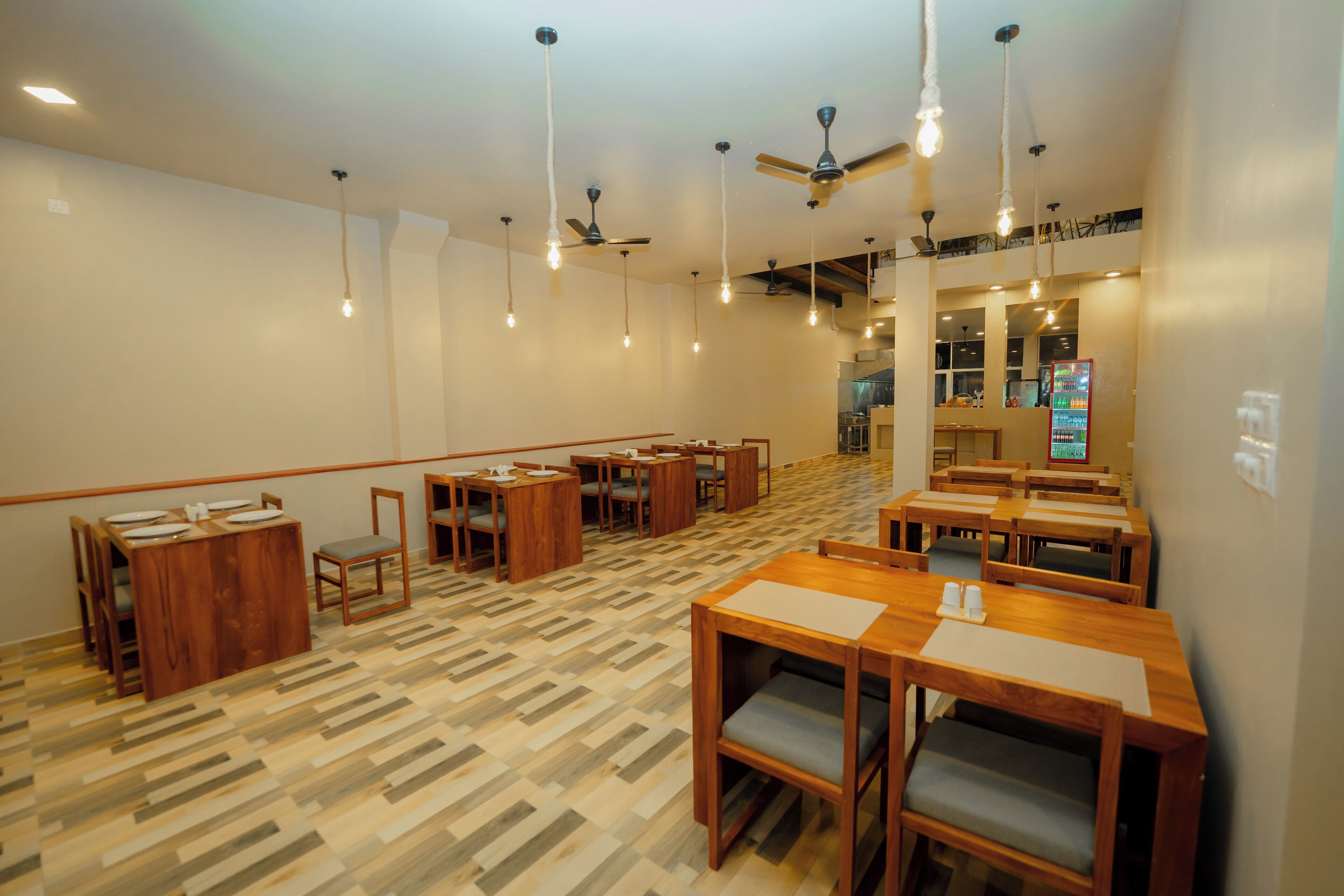 Ein Restaurant mit Holztischen und -stühlen, hängenden Lampen und Deckenventilatoren.