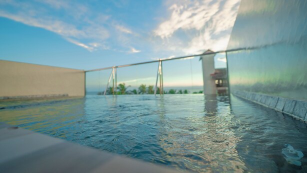 A swimming pool with a view of the sky and distant palm trees. - Emerald Resort Hikkaduwa (Hikkaduwa)
