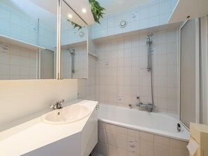 A modern bathroom with a large mirror, a sink, a bathtub, and a shower. - Studio with sea view and parking space (Middelkerke)