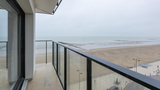 Een balkon met uitzicht op een strand en de zee.