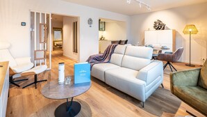 Una sala de estar moderna con un sofá blanco, una mesa de centro y un comedor con mesa y sillas.