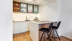 Una cocina moderna con armarios blancos, salpicadero de mármol y una isla integrada con taburetes de bar.