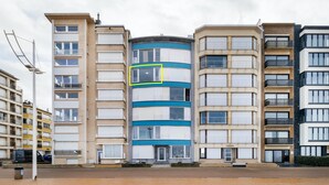 Un edificio residenziale a più piani con una facciata centrale blu e bianca, circondato da altri edifici.