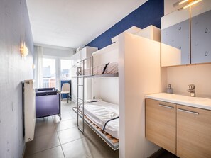A compact room with bunk beds, a desk, and a small kitchenette. - Beautiful flat with frontal sea views (Koksijde)