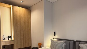 A modern hotel room with a large bed, a wooden wardrobe, a small bedside table, and a nightstand with a lamp. - Grand Hotel Mosh Mosh (Almaty)