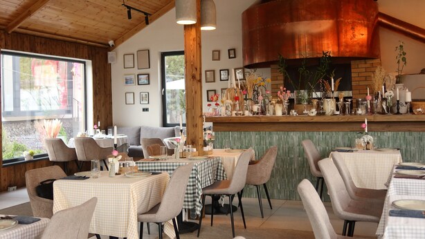 A restaurant with checkered tablecloths, wooden beams, and a copper stove. - Grand Hotel Mosh Mosh (Almaty)
