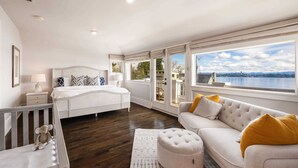 Quarto espaçoso com uma cama grande, um sofá e vista para a cidade.