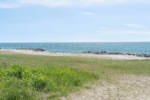 Ein Strand mit blauem Himmel, Sand und einigen Felsen.