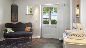 Ein Zimmer mit einer dunklen Couch, einer weißen Tür, einem Schrank und einem gefliesten Boden.