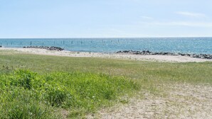 Ein Strand mit blauem Himmel, Sand und einigen Felsen.