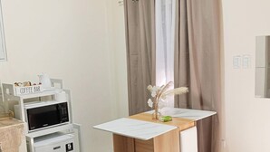 Quarto compacto com cozinha compacta, escrivaninha de madeira, cortina de chuveiro e um pequeno espelho de banheiro.
