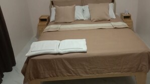 Cama bem arrumada com um espalha dourado, travesseiros brancos e uma toalha branca.
