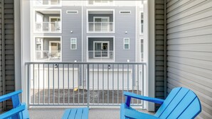 A balcony with two blue Adirondack chairs, a metal railing, and a view of a multi-story building with balconies and windows. - Pool Access! Newly Built Ocean City Townhome (Ocean City)