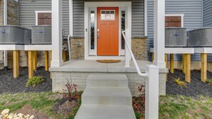 A two-story house with a red door, a front porch, and two air conditioning units on the ground floor. - Pool Access! Newly Built Ocean City Townhome (Ocean City)