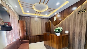 A reception area with a wooden reception desk, a sofa, and a clock on the wall. - Hotel Santosh Heritage (Pushkar)