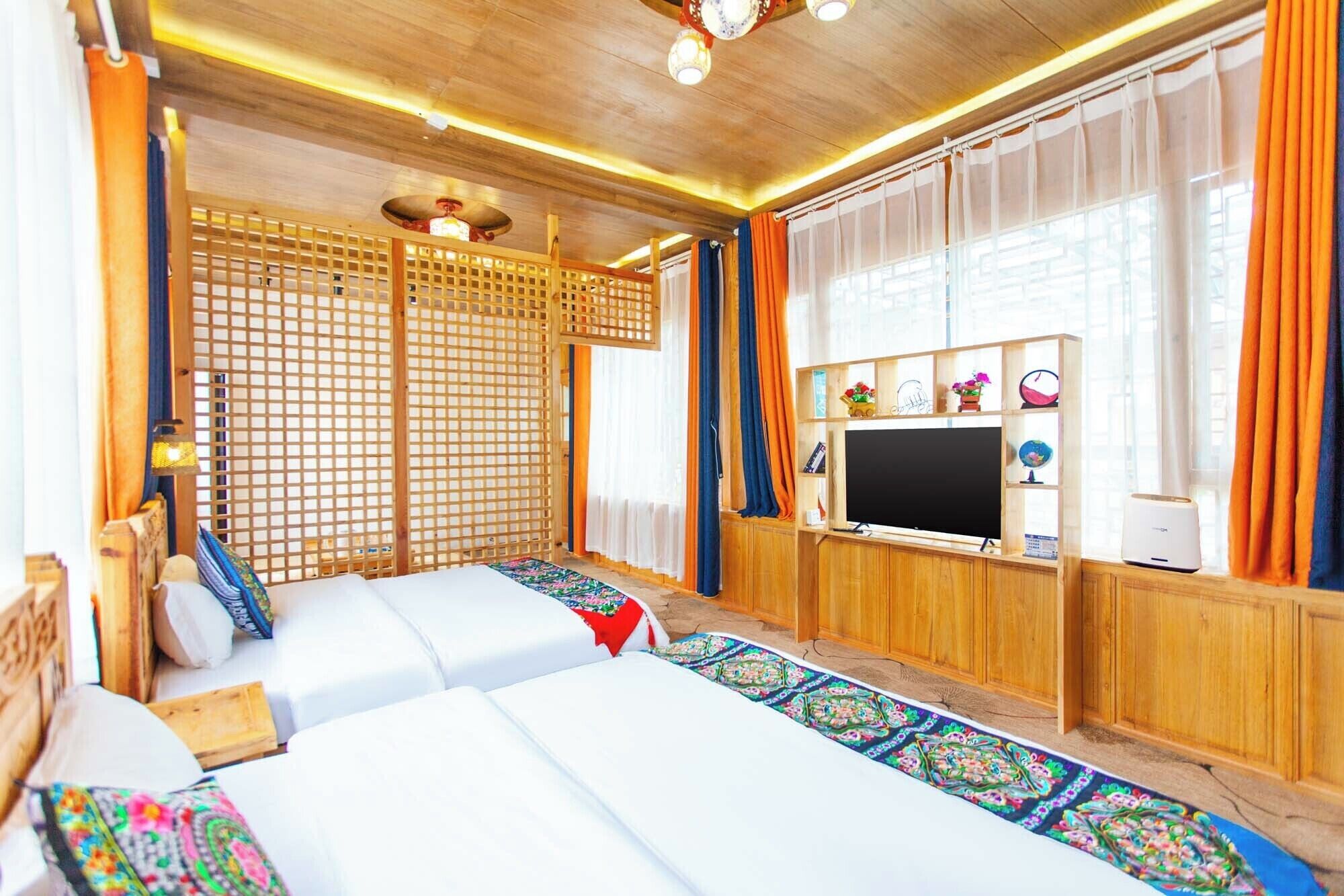 A room with two beds, a TV, and a wooden partition.