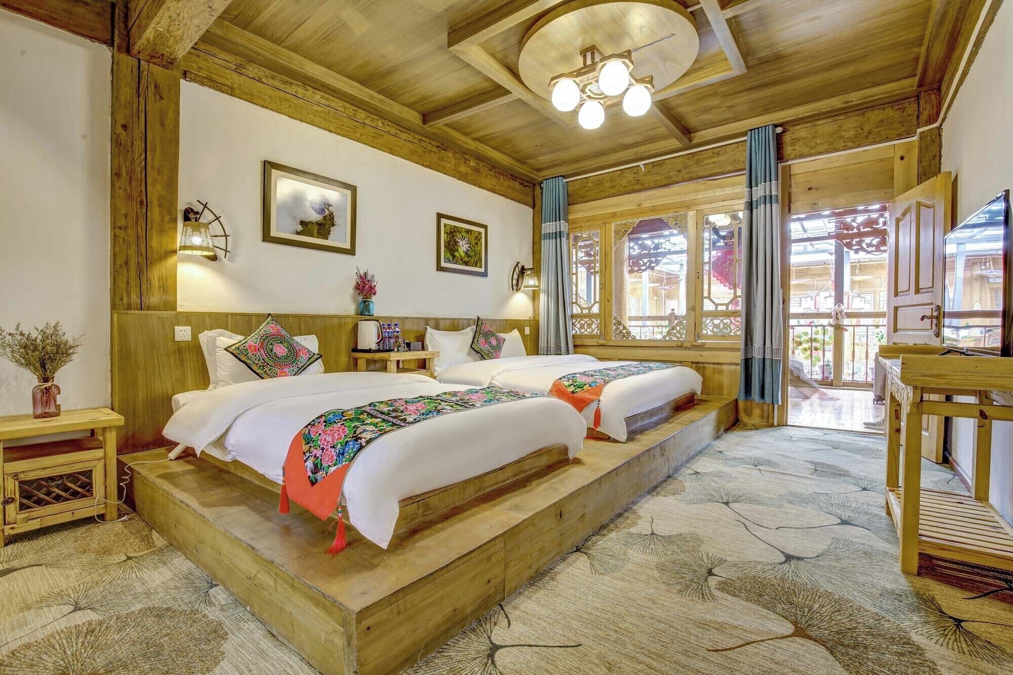 A traditional wooden room with two beds, a wooden bench, a small table, and a TV.
