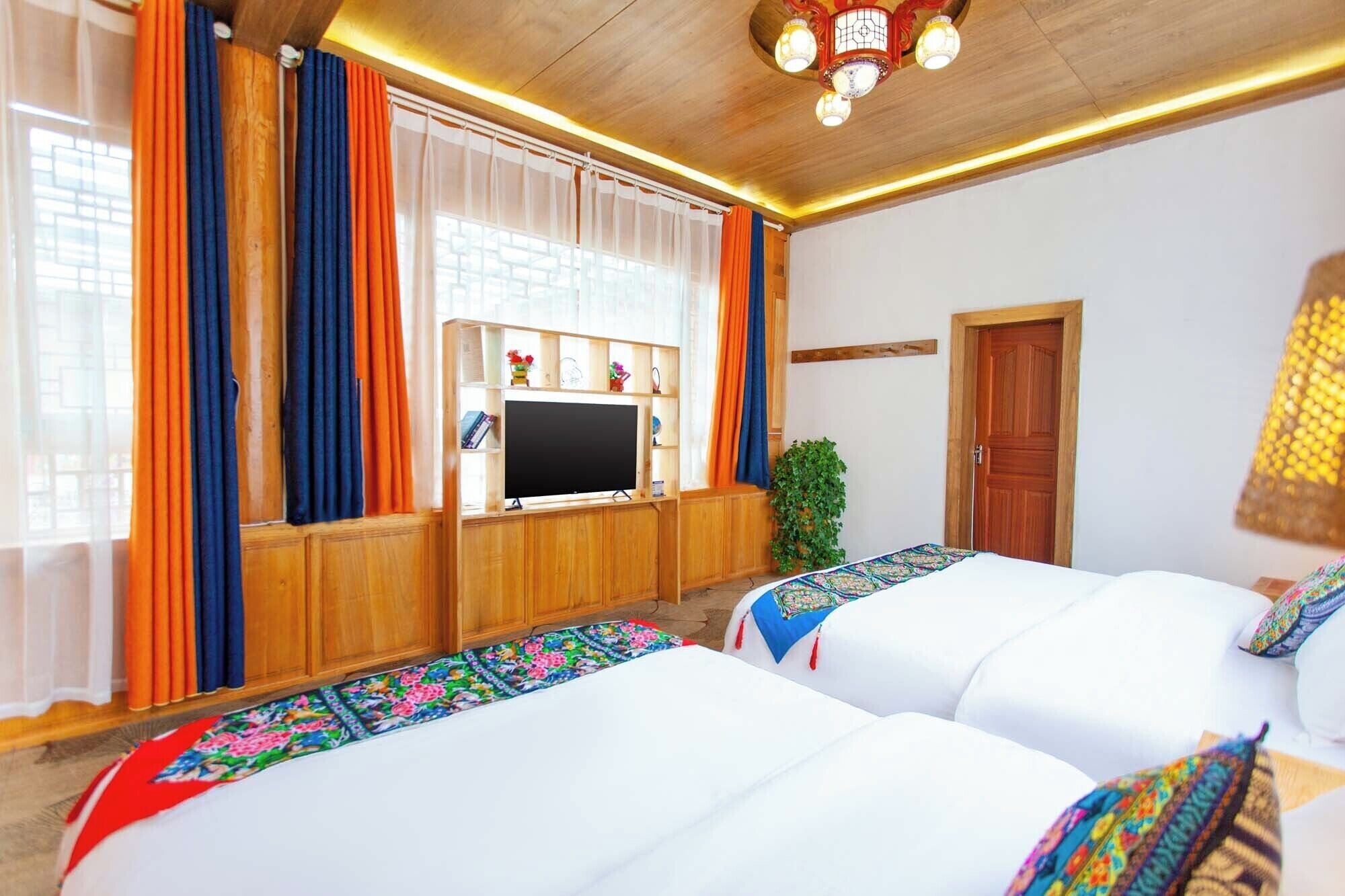 A hotel room with two beds, a TV, wooden paneling, and a ceiling light fixture.