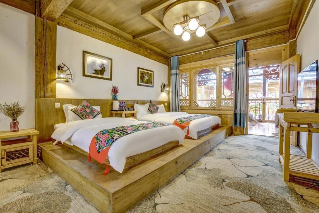 A traditional wooden room with a large bed, a small table, and a window with curtains.