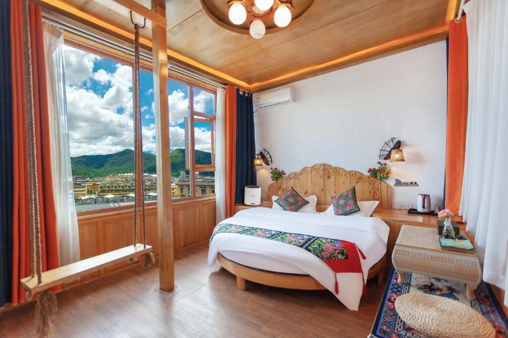A bedroom with a large bed, wooden headboard, and a view of a cityscape through large windows.