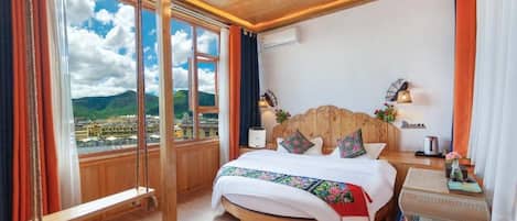 A bedroom with a large bed, wooden headboard, and a view of a cityscape through large windows.