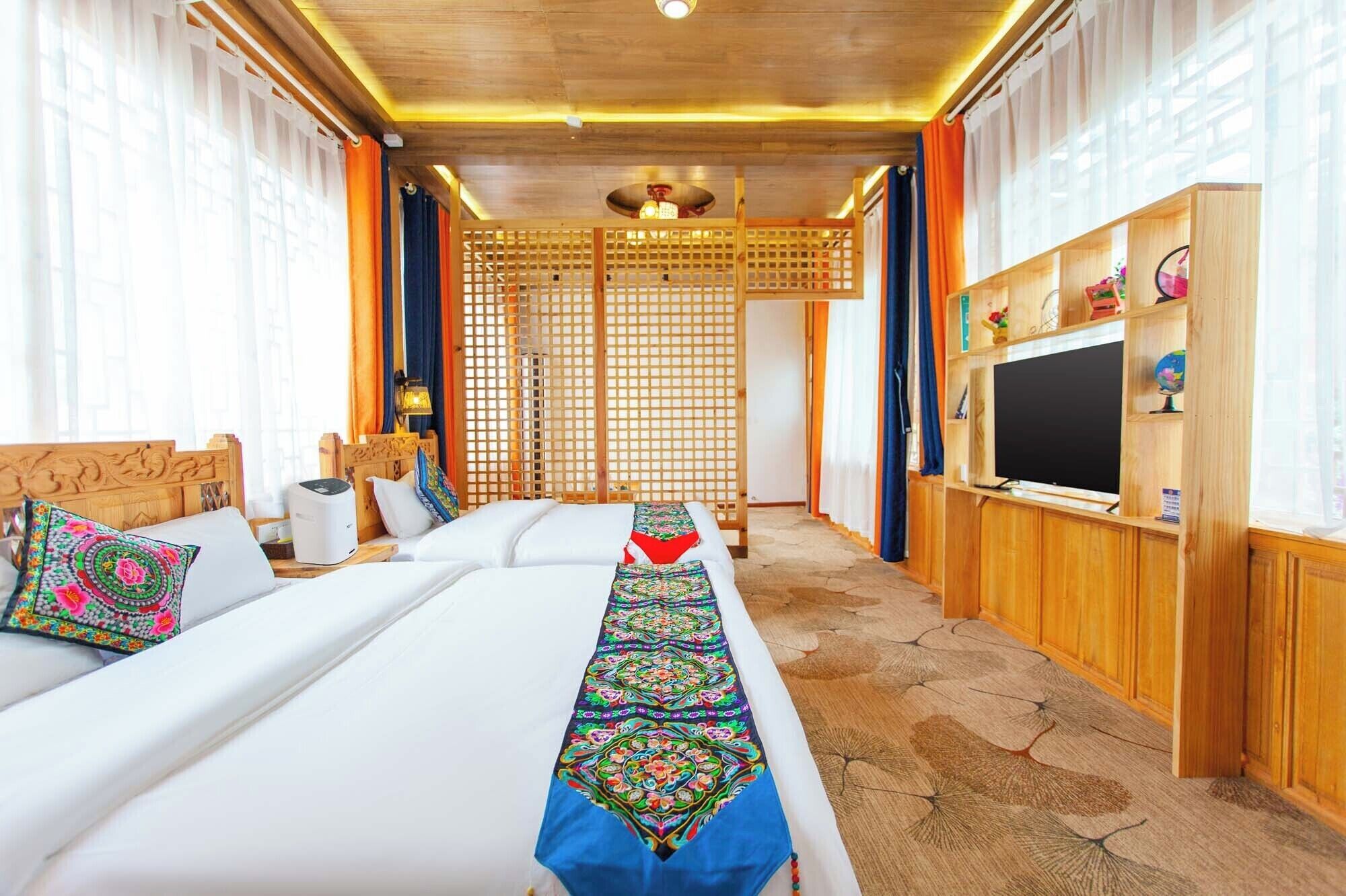 A hotel room with two beds, a TV, and a wooden cabinet with various items.