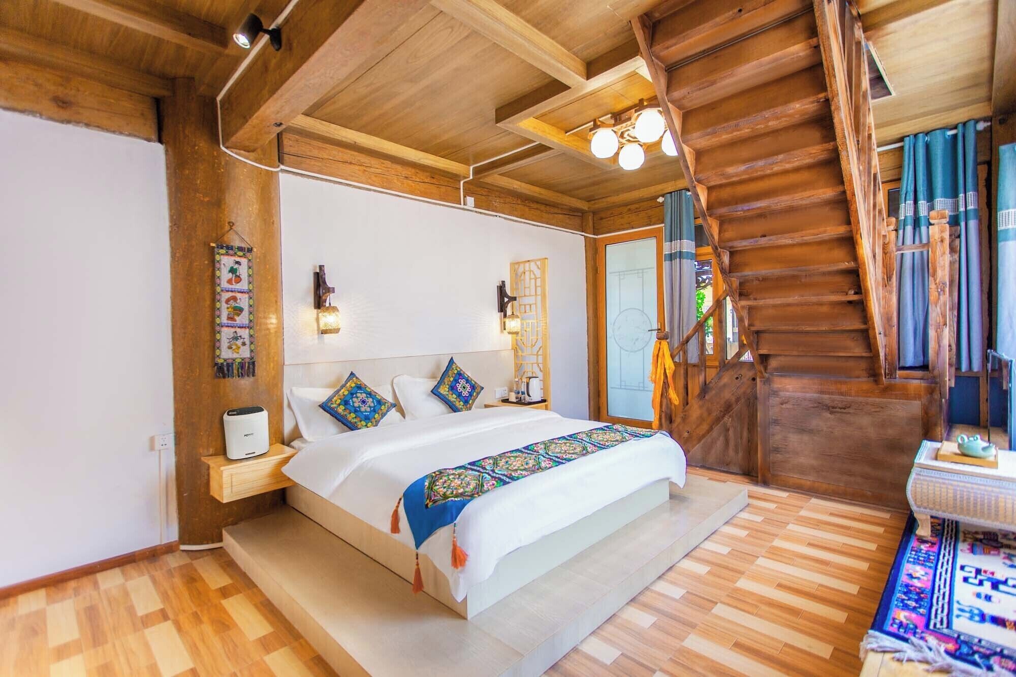 A wooden cabin-style bedroom with a bed, nightstands, a wall-mounted lamp, and a staircase.