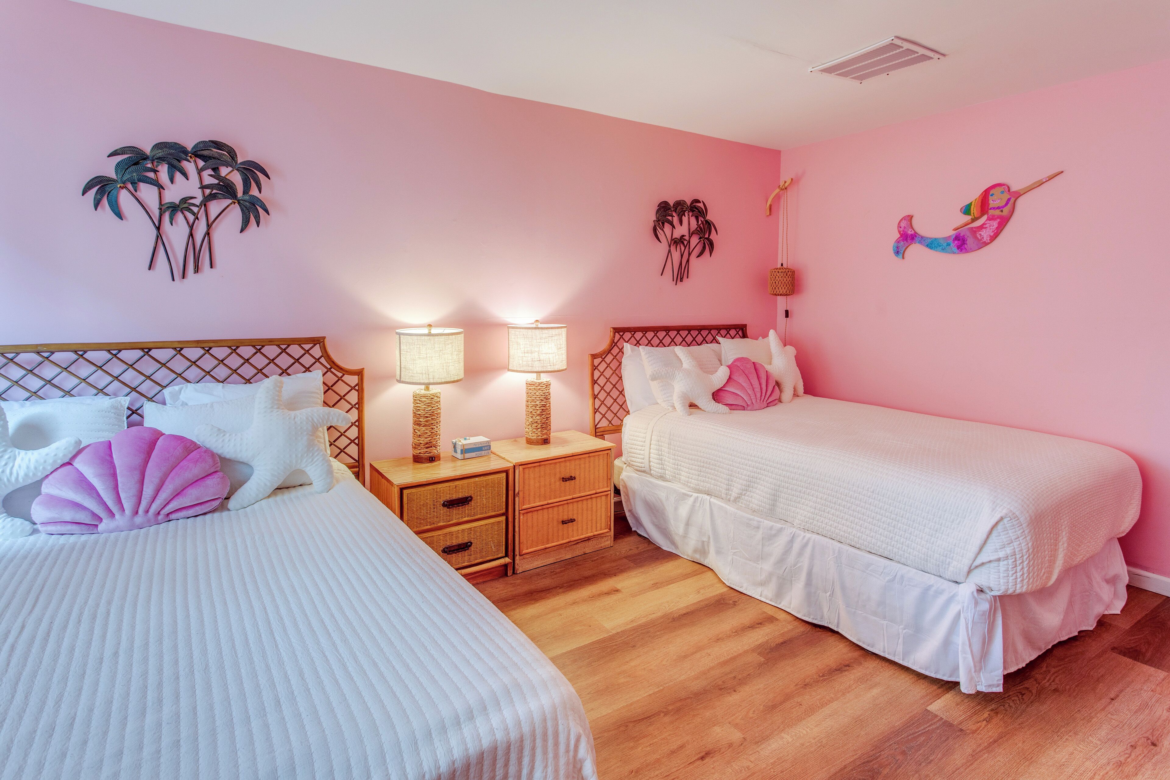 Ein Schlafzimmer mit zwei Betten, Holz-Kopfteilen, Nachttischen mit Lampen und dekorativen Wandbildern.