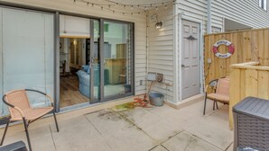 A covered patio with a sliding glass door leading to an interior space, a wooden fence with a lifebuoy decoration, and outdoor seating. - Golf, Explore & Walk to Shore! Myrtle Beach Unit (Myrtle Beach)