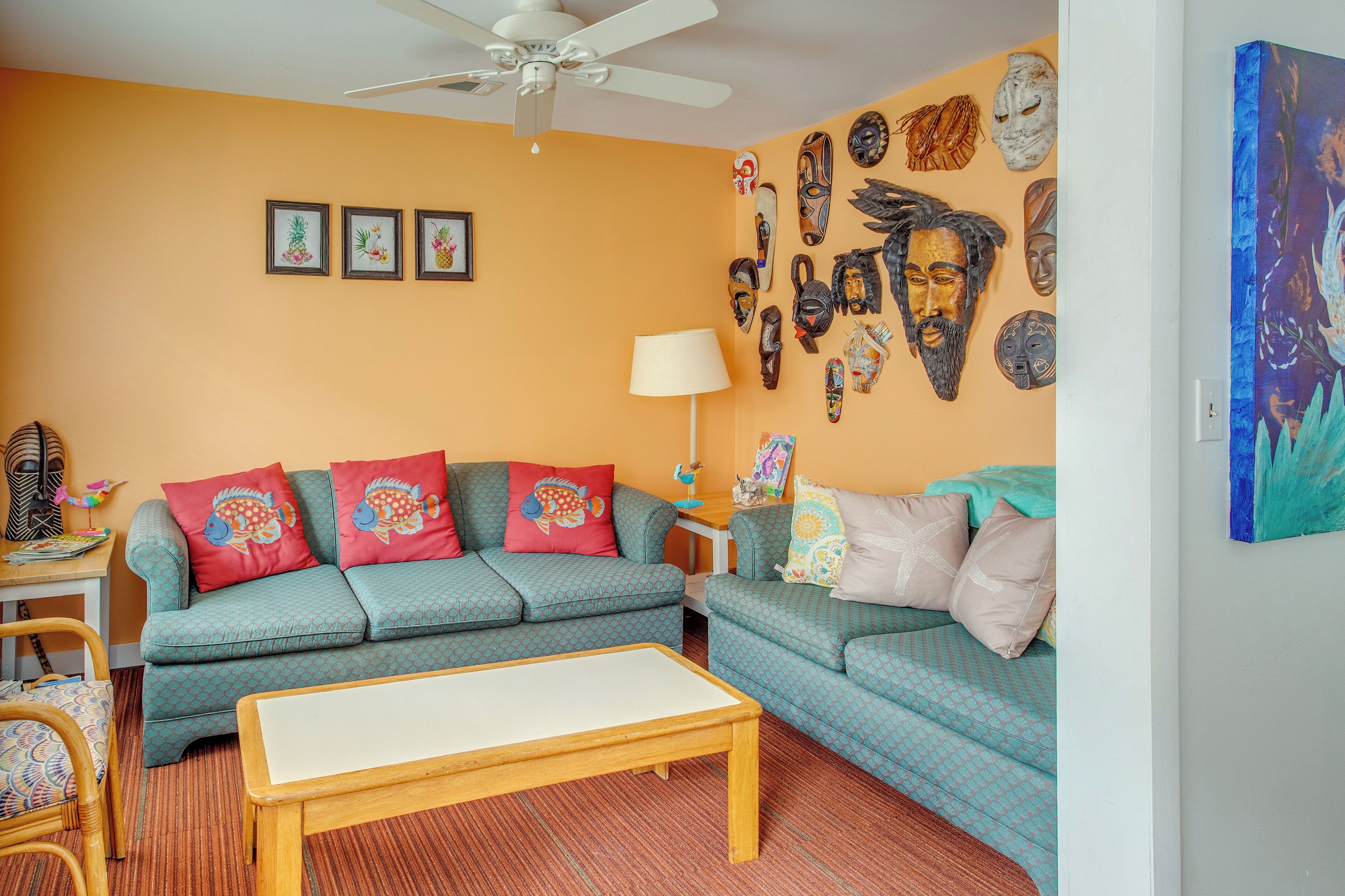 A living room with two sofas, a coffee table, and a ceiling fan.