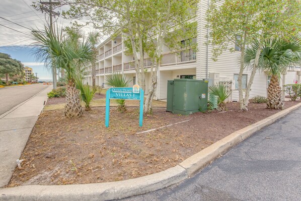 A multi-story hotel with balconies, palm trees, and a sign indicating the name and address. - Golf, Explore & Walk to Shore! Myrtle Beach Unit (Myrtle Beach)