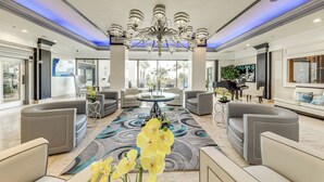 A spacious lobby with a chandelier, seating area, and a piano. - Steps to Sand! 10th-Floor Ocean Manor Unit w/ Pool (Fort Lauderdale)