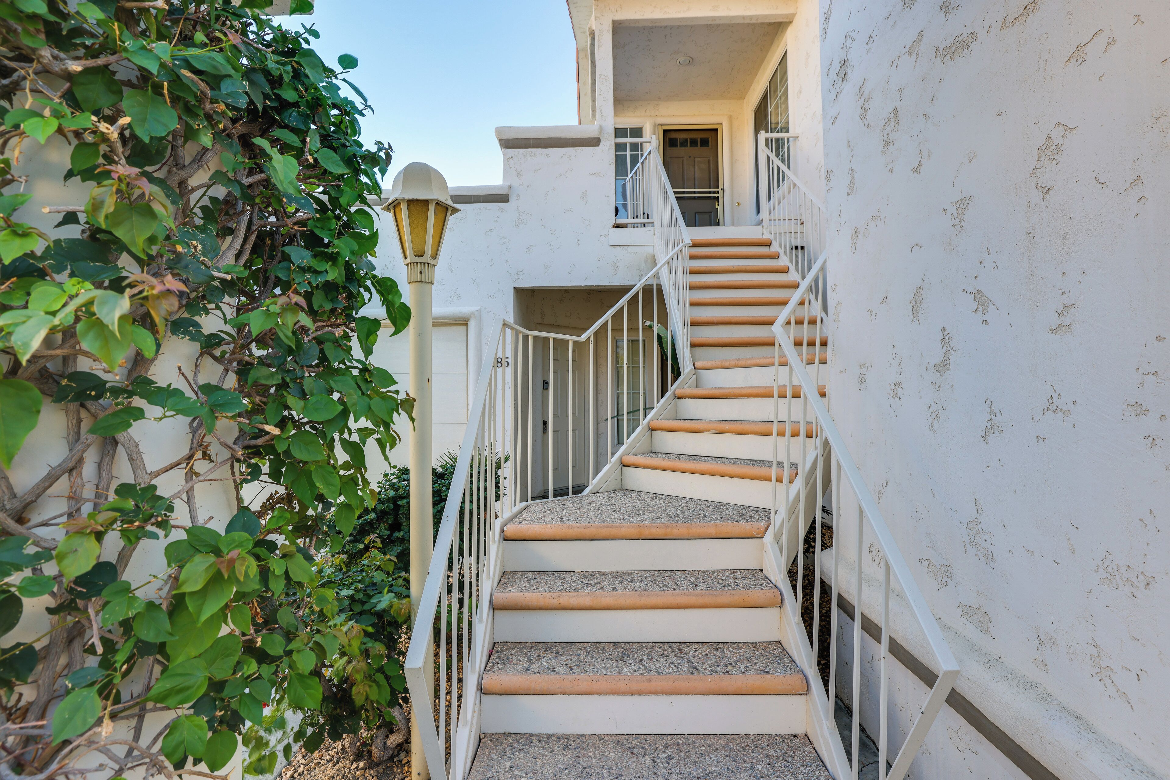 A staircase with white railings and wooden steps leading to a door.