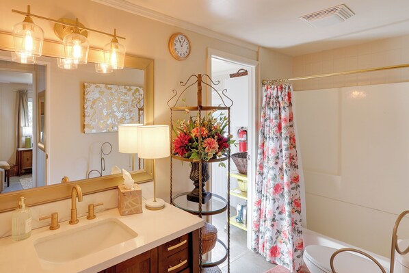 A bathroom with a sink, mirror, and a floral shower curtain.