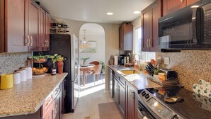 A modern kitchen with granite countertops, stainless steel appliances, and wooden cabinets. - Hualapai Mtn Views on 2 Acres: 'Thunderhead' Home (Kingman)