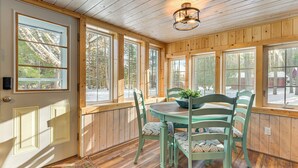 Una stanza con rivestimenti in legno, un tavolo da pranzo e sedie, ampie finestre e un lampadario.