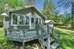 A cabin with a porch, a chimney, and a window with shutters. - Sturgeon River Retreat: Fish, Raft & Relax (Indian River)