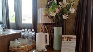 Een hotel receptiebalie met een waterdispenser, een waterkoker, een vaas met bloemen en een brochure over wellness.